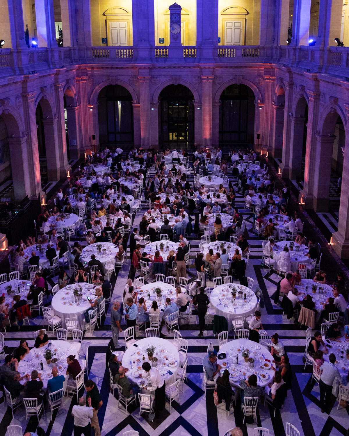 Un dîner de gala sous les arcades d'un grand hall, vu d'en haut